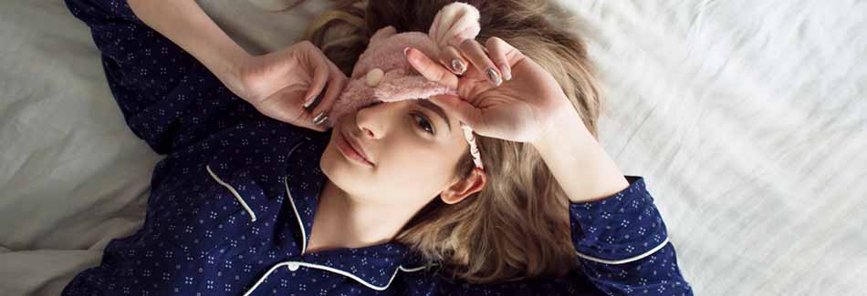 Schnell einschlafen: Eine Frau liegt mit Schlafmaske auf dem Bett