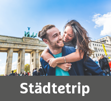 Glückliches junges Pärchen vor dem Brandenburger Tor in Berlin – Städtetrip mit H-Hotels
