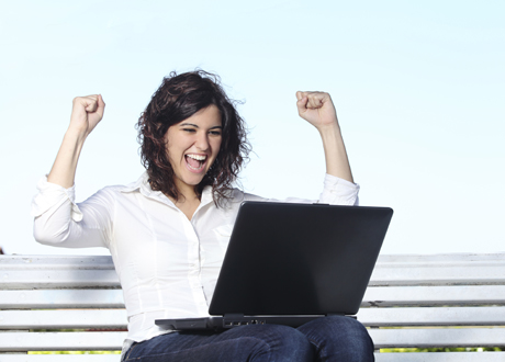 Frau freut sich an ihrem Laptop auf einer Parkbank – PAYBACK Punkte bei Best Western sammeln und sparen 