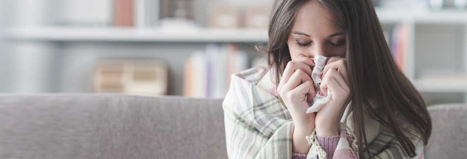 Erkältung vorbeugen: Eine erkältete Frau putzt sich die Nase